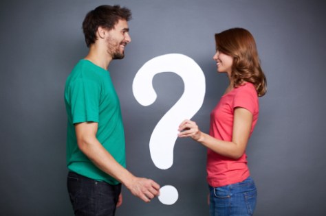 Portrait of young couple holding paper question mark and looking at on another